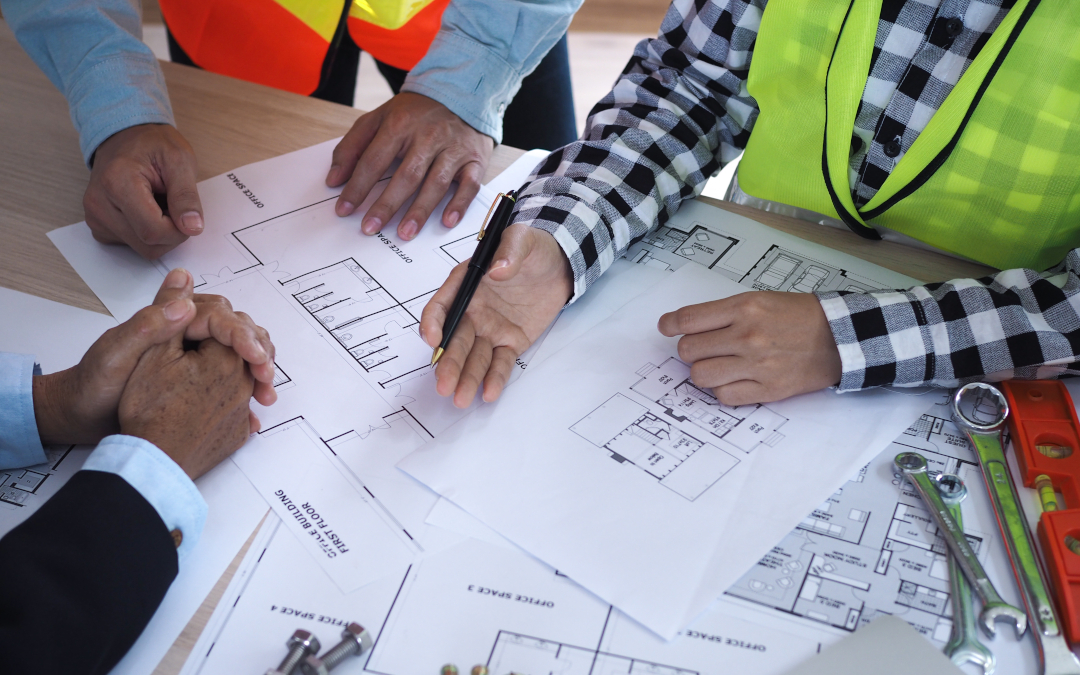 Owners, Developers And Property Managers - photo with 3 men at table with plans and drawings on table